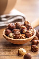 Peeled hazelnut kernels on spoon on wooden table.
