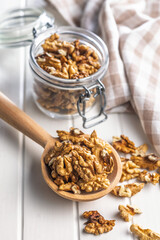 Peeled walnut kernels on wooden spoon on white table.