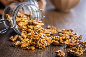 Peeled walnut kernels in jar on wooden table.