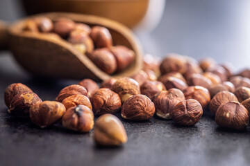 Peeled hazelnut kernels on black table.