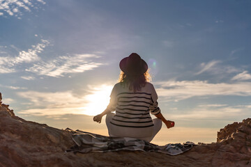Meditation sunset silhouette woman practicing yoga pose on rocky cliff with peaceful expansive sky