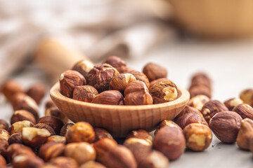 Peeled hazelnut kernels on wooden spoon on kitchen table.