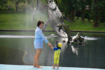 Mother and Child Near Fountain with Dolphin Sculpture in Park