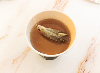 Tea bag steeping in a cup on a marble table