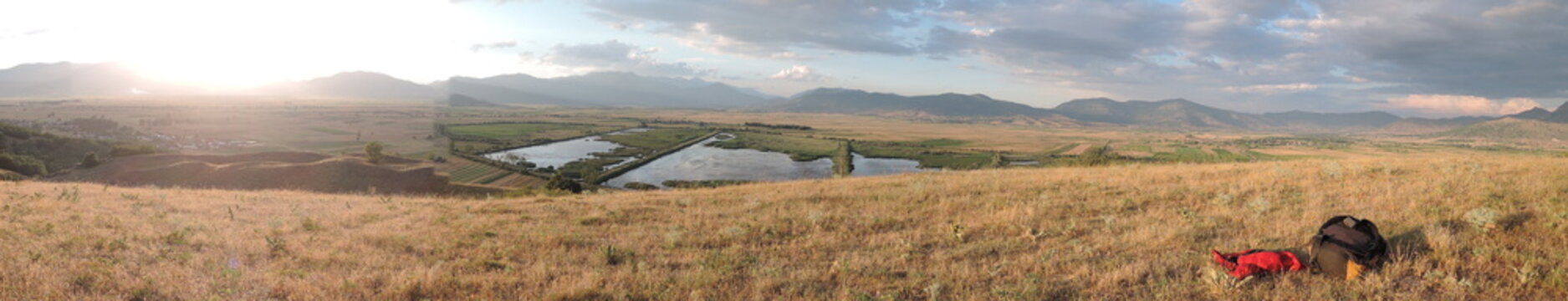 Macedonia wide panoramic view of Macedonian mountains and open green meadows under bright summer sunlight, showing rolling hills dry grass textures and clear sky on a hot day in the Balkan countryside