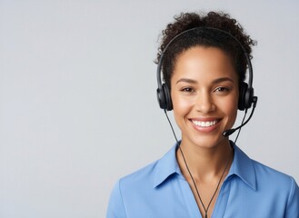 Cheerful Black woman with curly hair wearing headset and blue shirt, smiling at camera with left copy space
