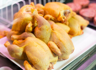 Fresh whole chickens in the window of a butcher shop, prepared for sale close up. Meat department in a supermarket with fresh products