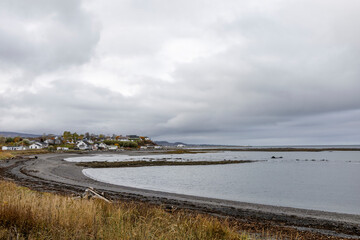 Peaceful riverside view on the south shore of the St. Lawrence River, showcasing a quaint village under cloudy skies.