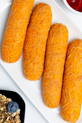 Healthy continental breakfast with corn sticks, granola with blueberries, orange juice, and red fruit and cherry jams on a white background.