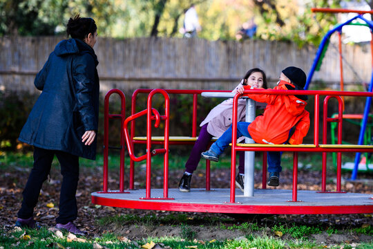 Woman pushing children on a merry-go-round