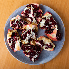 Slices of ripe pomegranate with juicy grains on a gray plate top view