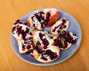 Slices of ripe pomegranate with juicy grains on a gray plate top view