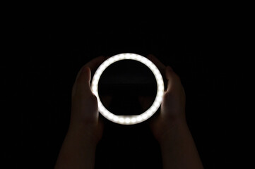 The silhouette of two hands touching a white circle on a black background. Pressing the start or beginning button.