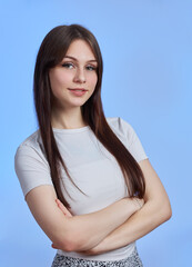 Portrait of a young beautiful student girl in a white T-shirt isolated on a blue background