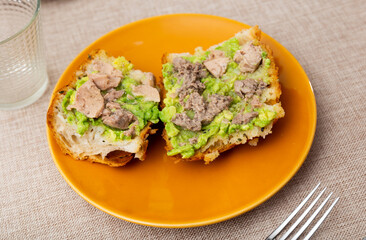 Cod liver and avocado sandwiches. Hearty snack is made using baguette and canned cod liver.