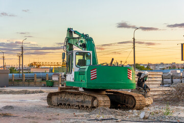 Obraz premium Excavator working at a construction site during sunset in an urban landscape