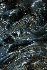 Textura abstracta de roca metamórfica oscura y brillante, mojada por el agua del Río Santo Domingo en El Carmen de Viboral, Antioquia, Colombia. Geología, patrón natural y contraste.