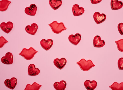 Pattern of red glitter hearts and lip appliqués randomly placed on a pink background