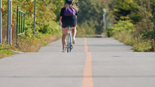 Cinematic Scene Showing Female Cyclists Enjoying A Ride Through The City Park Surrounded By Yellow Trees, Promoting A Healthy Active Lifestyle.
