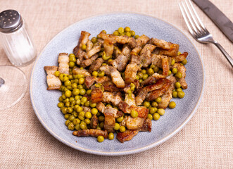 Pieces of fried pork belly with green peas