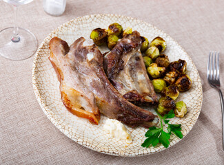 Cooked pork ribs with spices and Brussels cabbage on a round ceramic plate with cutlery
