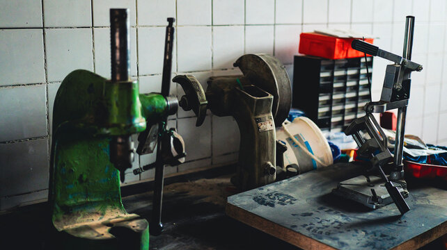 Dusty vintage workshop with heavy drill press, cluttered workbench and clear boot print in the dust — authentic retro craftsmanship scene