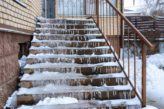 Hazardous icy staircase and frozen sidewalks in a quiet residential area, showing winter conditions that increase the risk of slips and falls.