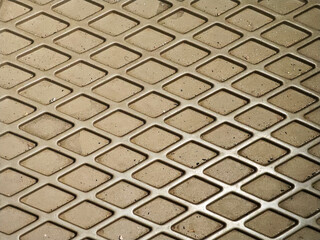 Close-up showcases a pattern of diamond shapes. The texture is rough and somewhat dirty, adding depth and character to the surface. Ideal for backgrounds or textures. Versatile for creative uses.