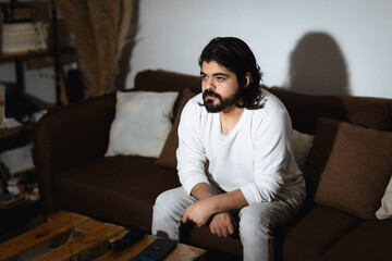 Obraz premium Man Watching TV with Remote Control in Dramatic Light