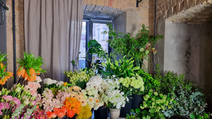 Colorful display of fresh flowers arranged in black buckets inside a florist shop. A variety of vibrant blooms pink tulips, roses, white flowers, greenery, and mixed seasonal plants in flower shop