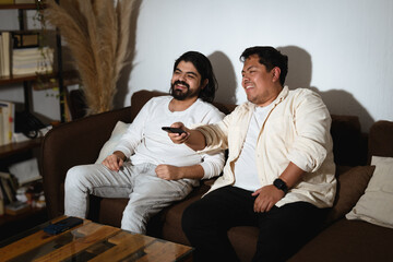 Obraz premium Two Friends Laughing While Watching TV Together at Night