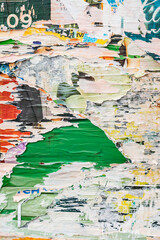 Ripped paper background revealing vivid green, orange, and pastel posters layers. Concept of urban layering, vibrant decay, and retro visual storytelling