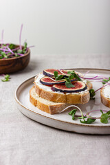 Slices of white bread with young cream cheese, freshly sliced figs and radish sprouts.