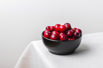 Cranberries in black bowl on white table