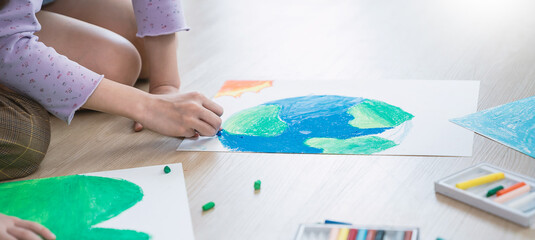 Group of kids hands drawing with crayons on the floor during an art activity in a bright classroom setting. Education back to school earth day concept