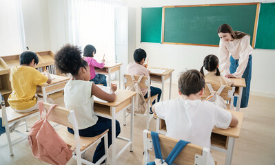  Portrait of little caucasian pupil writing at desk in classroom at elementary school. Student girl study doing test in primary school. Children writing notes in classroom. Education knowledge banner