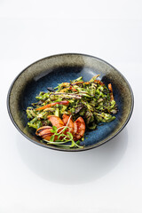 Warm grilled vegetable salad with pesto and balsamic in black bowl, top view