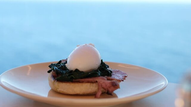 Egg benedict with hollandaise sauce cooking video cook eggs benedict poached egg pour sauce on sandwich