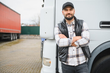 Professional truck driver standing with arms crossed by semi truck