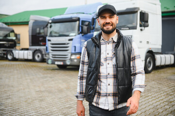 Smiling truck driver standing in front of semi trucks