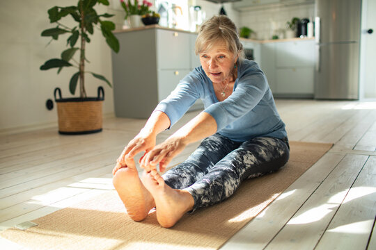 Senior woman focused on seated yoga stretch at home