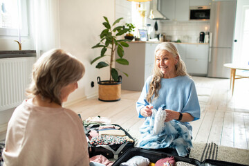 Senior lesbian couple smiling while packing luggage at home