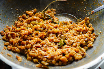 A close-up shot showcasing savory minced ingredients sauteed in a metal wok, creating a warm and inviting atmosphere. The texture is rich, and the color palette is earthy and rustic.