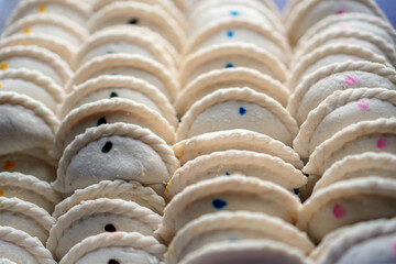 Close-up of a pile of homemade cookies or sweets, with a simple filling dot that varies in color. The treats are neatly arranged, showcasing their detailed edges and sweet character.