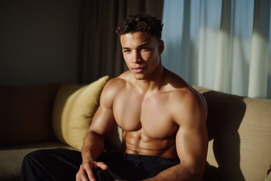 Shirtless muscular man sitting on couch