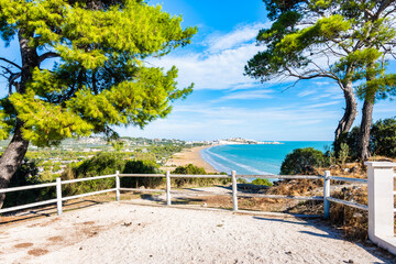 Scenic viewpoint framed by pine trees overlooking the long sandy beach and town of Vieste, Apulia, Italy