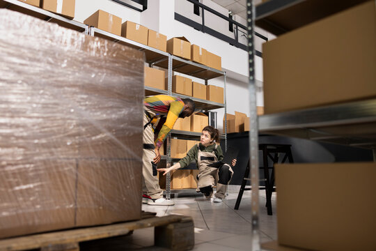 Diverse employees checking stock and packaging goods for delivery in small business depot, ensuring inventory processing and product handling for online orders and wholesale distribution.