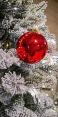 Festive close-up of a Christmas tree adorned with red, white, and silver ornaments, highlighting intricate designs against frosted greenery, creating a holiday atmosphere.