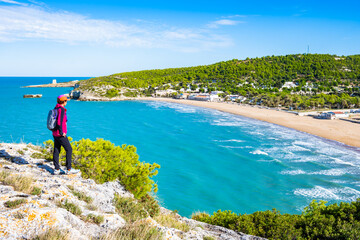 Female tourist at scenic viewpoint overlooking the Adriatic coast and golden beach near Peschici, Apulia, Italy