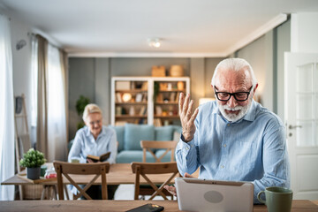 Senior man video calling using digital tablet at home
